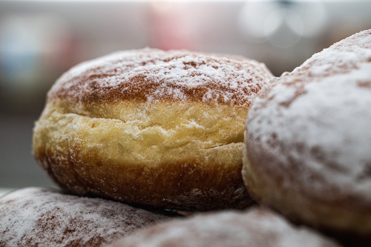 Close-up of freshly baked Berliner donuts with powdered sugar. Ideal for food and culinary content.