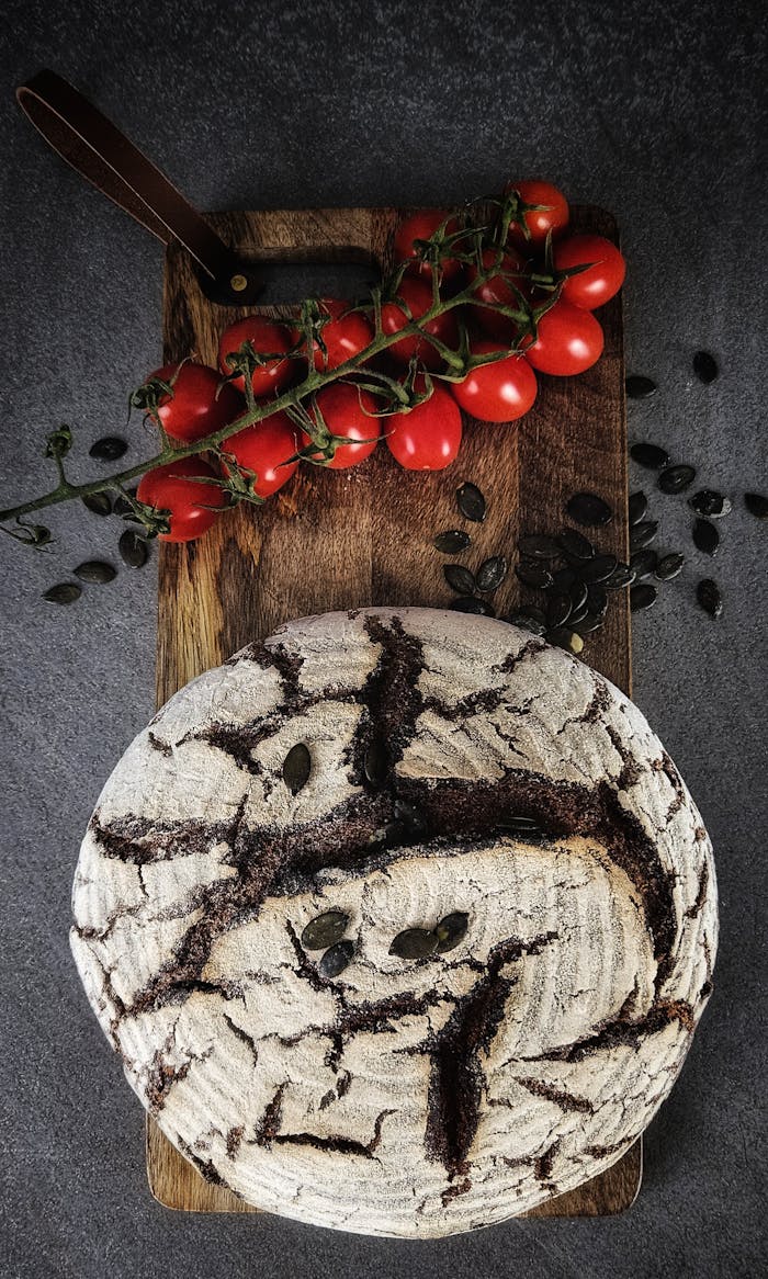 Freshly baked rustic bread on a wooden board with vine ripened tomatoes.